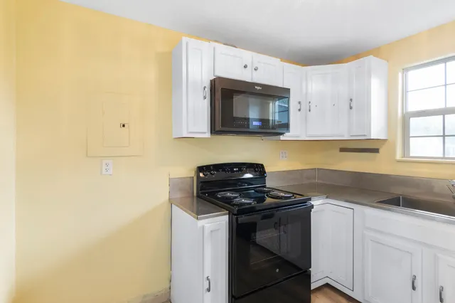 a kitchen with stainless steel appliances granite countertop a sink and a stove next to a window