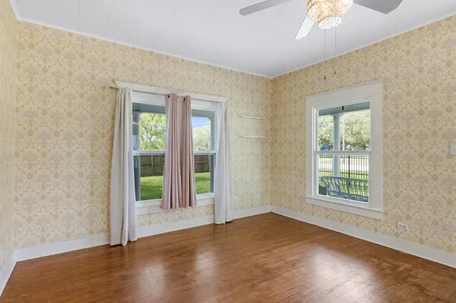 an empty room with wooden floor and windows