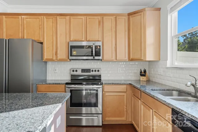 a kitchen with granite countertop a sink stove and microwave