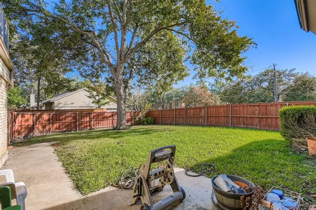 a view of a backyard with couches plants and large trees