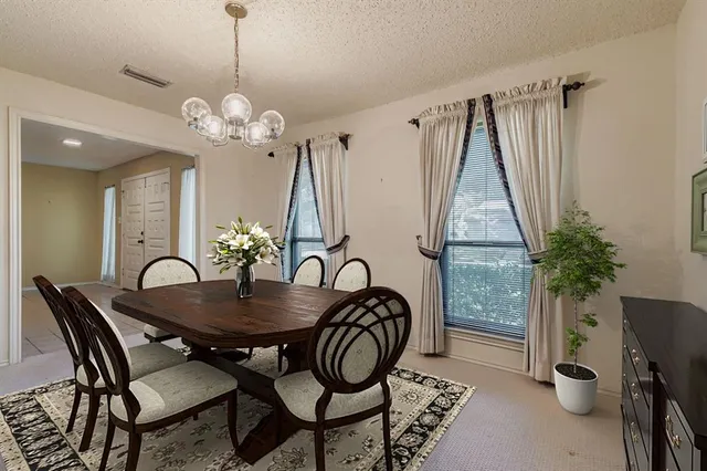 a dining room with chandelier and wooden floor