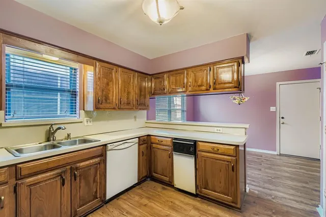 a kitchen with granite countertop cabinets stainless steel appliances a sink and wooden floor