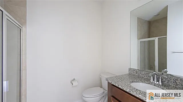 a bathroom with a granite countertop toilet sink and mirror