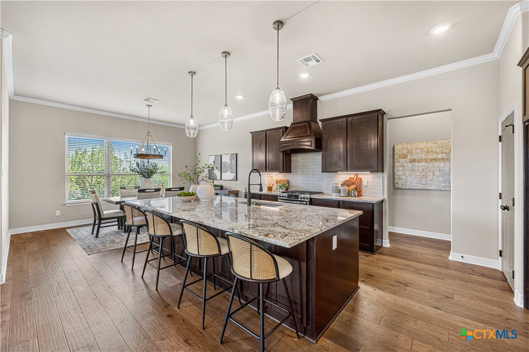 2136 Oak Draw Court Belton, TX 76513 - Photo 6 of 46 a kitchen with granite countertop a table chairs stainless steel appliances and wooden floor