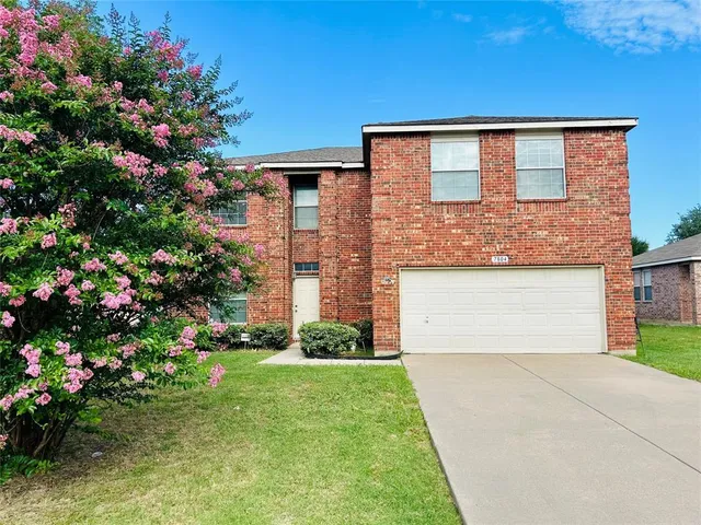 a front view of house and yard with beautiful flowers