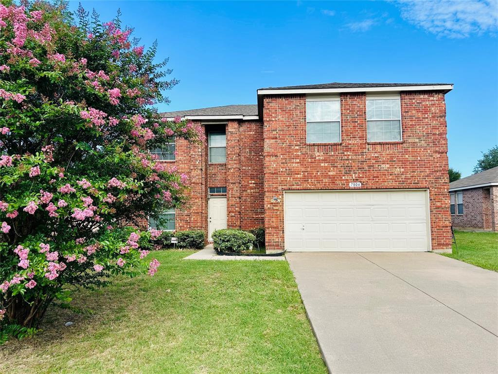 a front view of house and yard with beautiful flowers