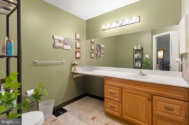 a bathroom with a granite countertop sink a toilet and mirror