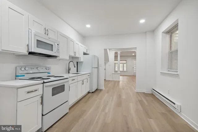 a kitchen with stainless steel appliances granite countertop a stove top oven a sink dishwasher and a refrigerator with wooden floor