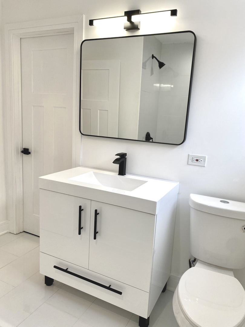 Undisclosed Address Chicago, IL 60617 - Photo 11 of 29 a bathroom with a sink mirror vanity and toilet