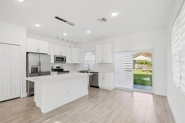 a kitchen with stainless steel appliances a refrigerator a stove a sink cabinets and wooden floor