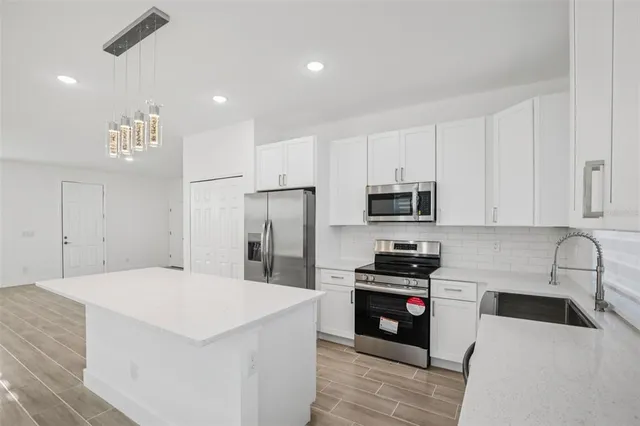 a kitchen with granite countertop a refrigerator sink and white cabinets