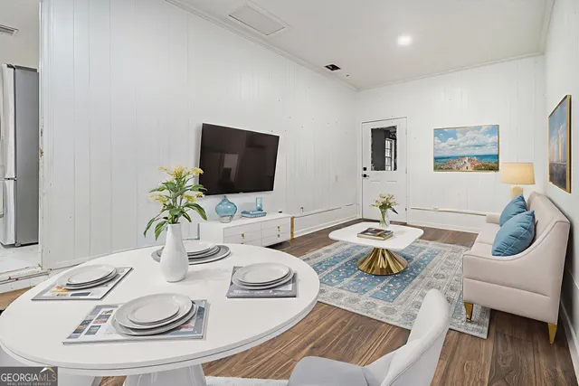 a dining room with furniture a wooden floor and a flat screen tv