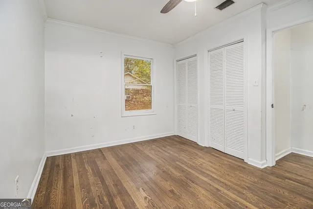 an empty room with wooden floor and windows