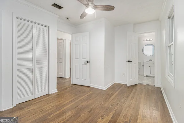 an empty room with wooden floor and a ceiling fan
