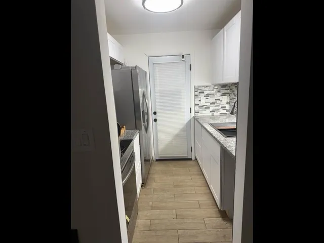 a kitchen with stainless steel appliances granite countertop a refrigerator and a sink