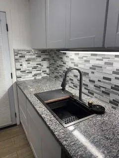 a kitchen with granite countertop a sink and a stove
