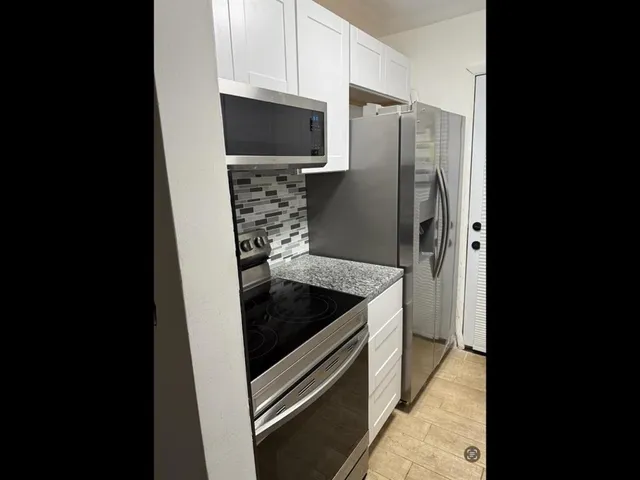 a kitchen with granite countertop a stove and a refrigerator