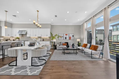 a living room with furniture kitchen view and a chandelier