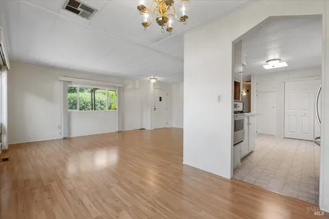 an empty room with wooden floor and a kitchen