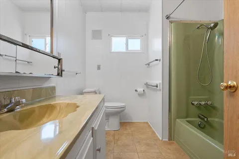a bathroom with a granite countertop bathtub shower sink and toilet