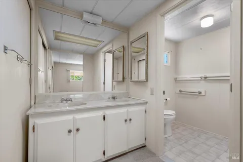 a bathroom with a granite countertop sink toilet and mirror