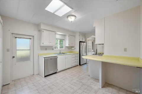 a large white kitchen with a sink and dishwasher a refrigerator with white cabinets