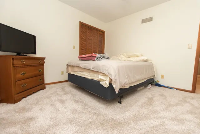 a spacious bedroom with a bed and a flat screen tv