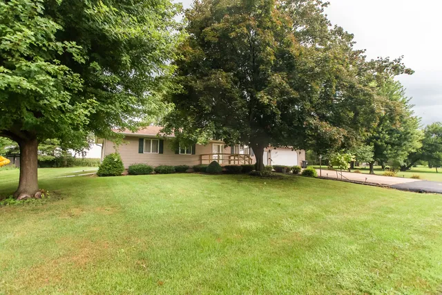 a view of a house with a big yard and large trees