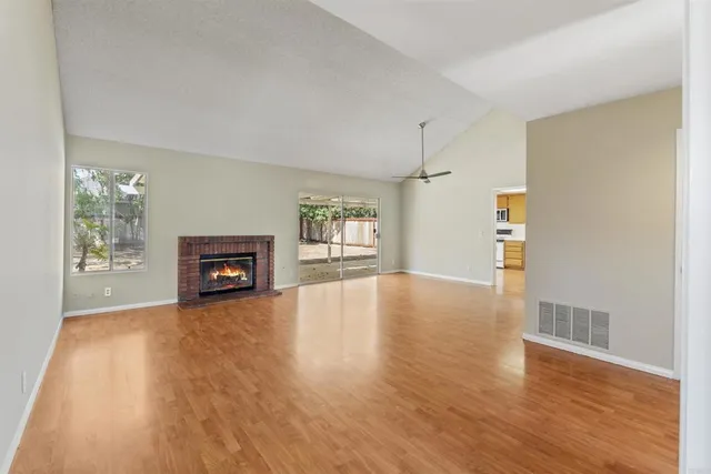 a view of an empty room with a window and wooden floor