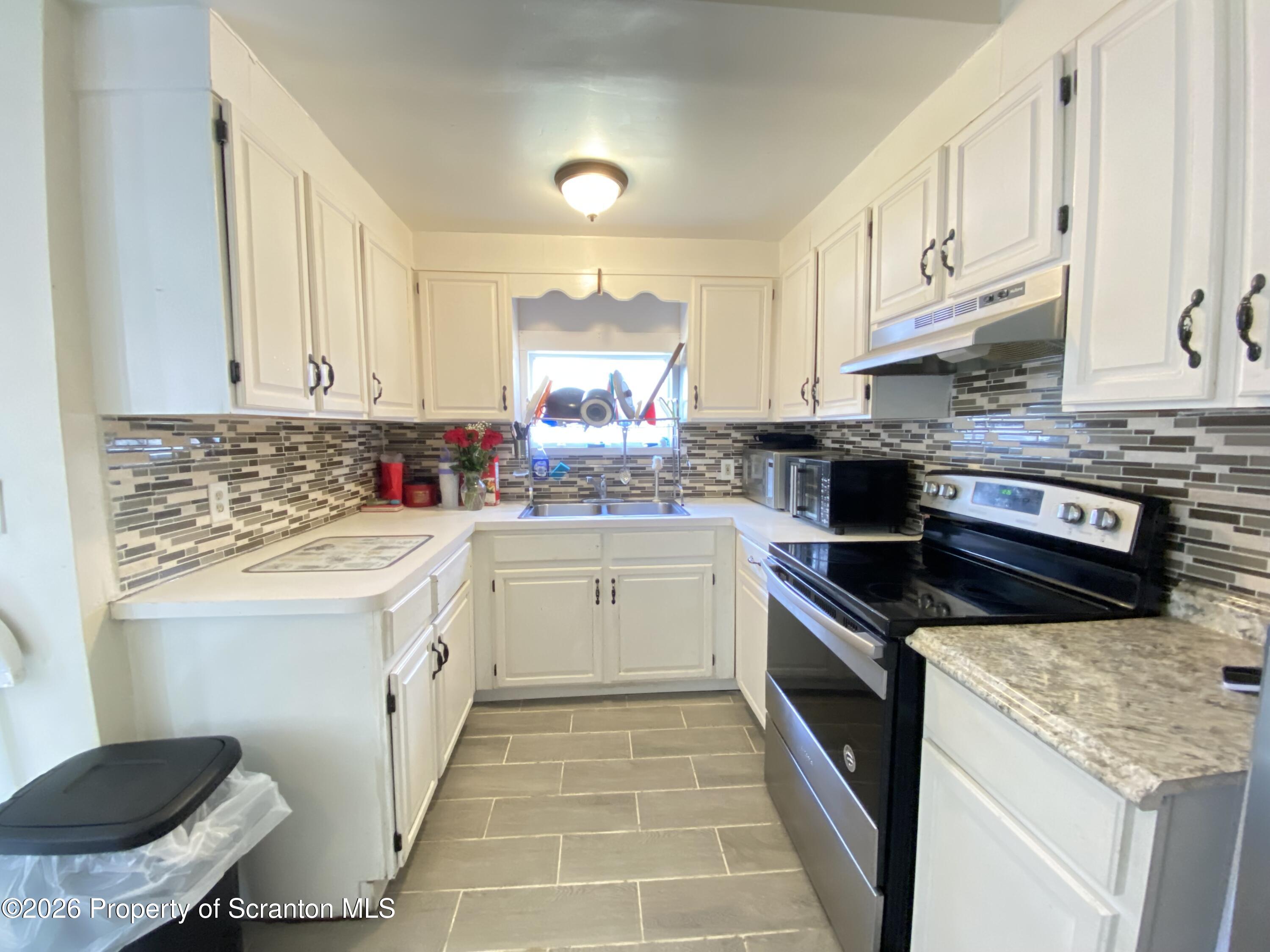 2115-2117 Wayne Avenue Scranton, PA 18508 - Photo 11 of 44 a kitchen with granite countertop a sink stainless steel appliances and cabinets