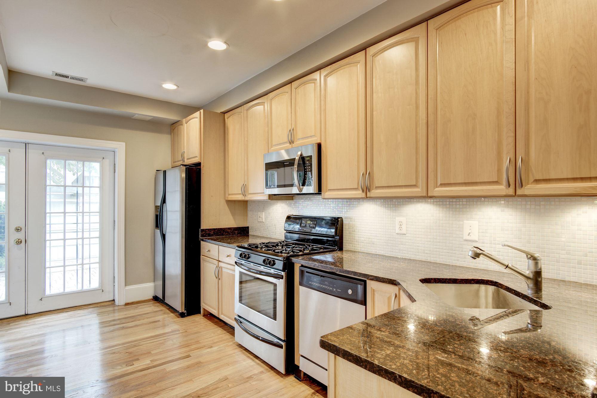 1414 D Street Northeast Washington, DC 20002 - Photo 7 of 25 a kitchen with stainless steel appliances granite countertop a stove a sink and a microwave