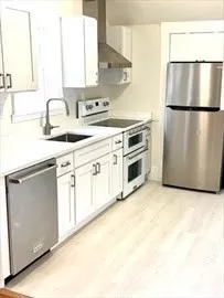 a kitchen with stainless steel appliances granite countertop a sink a stove a refrigerator with white cabinets