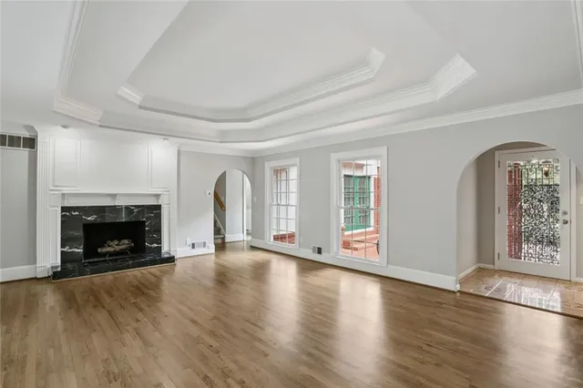 an empty room with wooden floor fireplace and windows