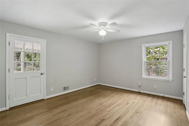 a view of an empty room with wooden floor and a window