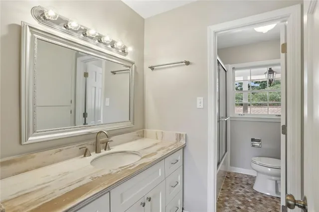a bathroom with a granite countertop sink a toilet and a mirror