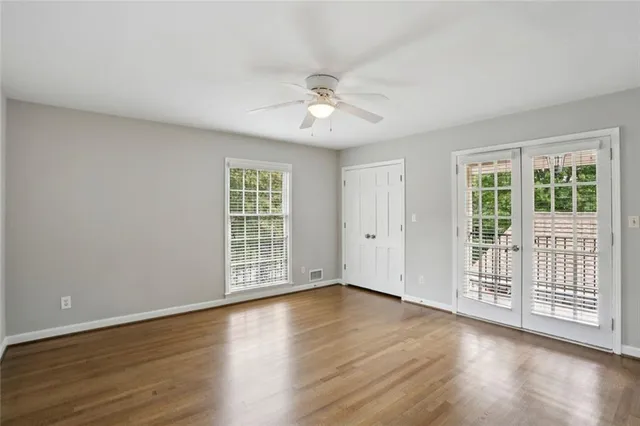 a view of an empty room with wooden floor and a window