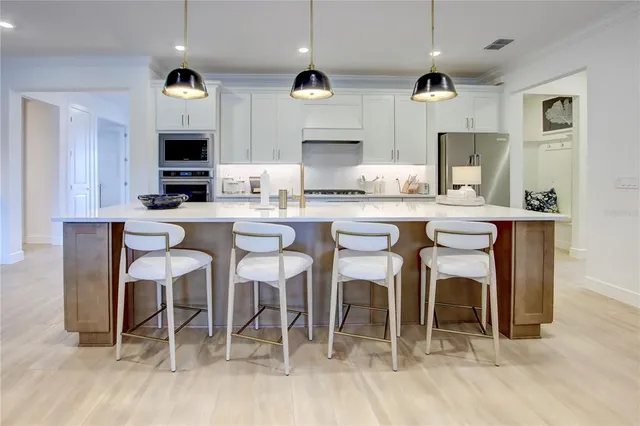 a kitchen with stainless steel appliances kitchen island granite countertop a table chairs sink and cabinets