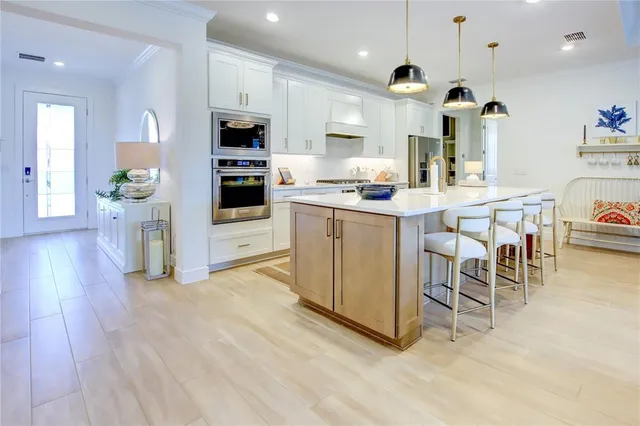 a kitchen with stainless steel appliances kitchen island granite countertop a stove top oven a sink dishwasher and a refrigerator with wooden floor