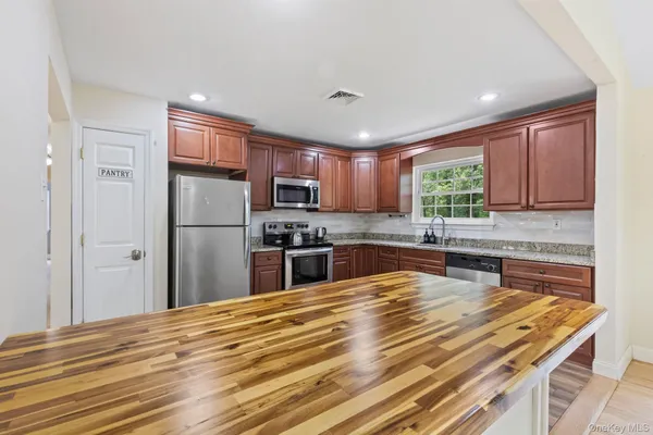 a kitchen with granite countertop stainless steel appliances a refrigerator cabinets and wooden floor