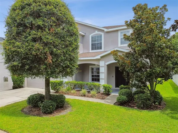 a front view of a house with a yard and trees