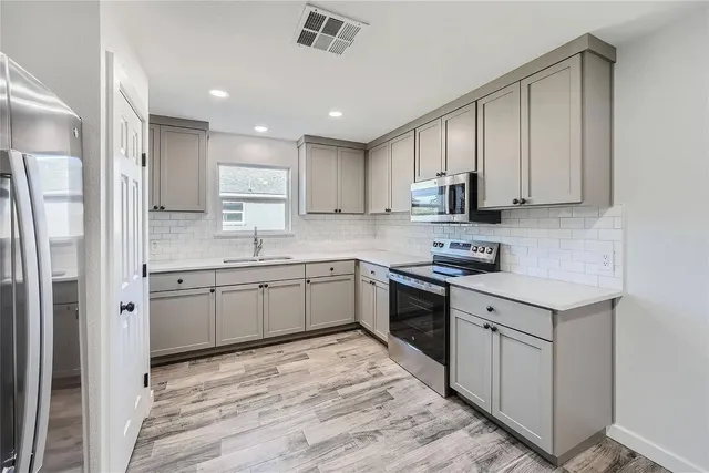 a kitchen with stainless steel appliances granite countertop a stove a sink and a refrigerator