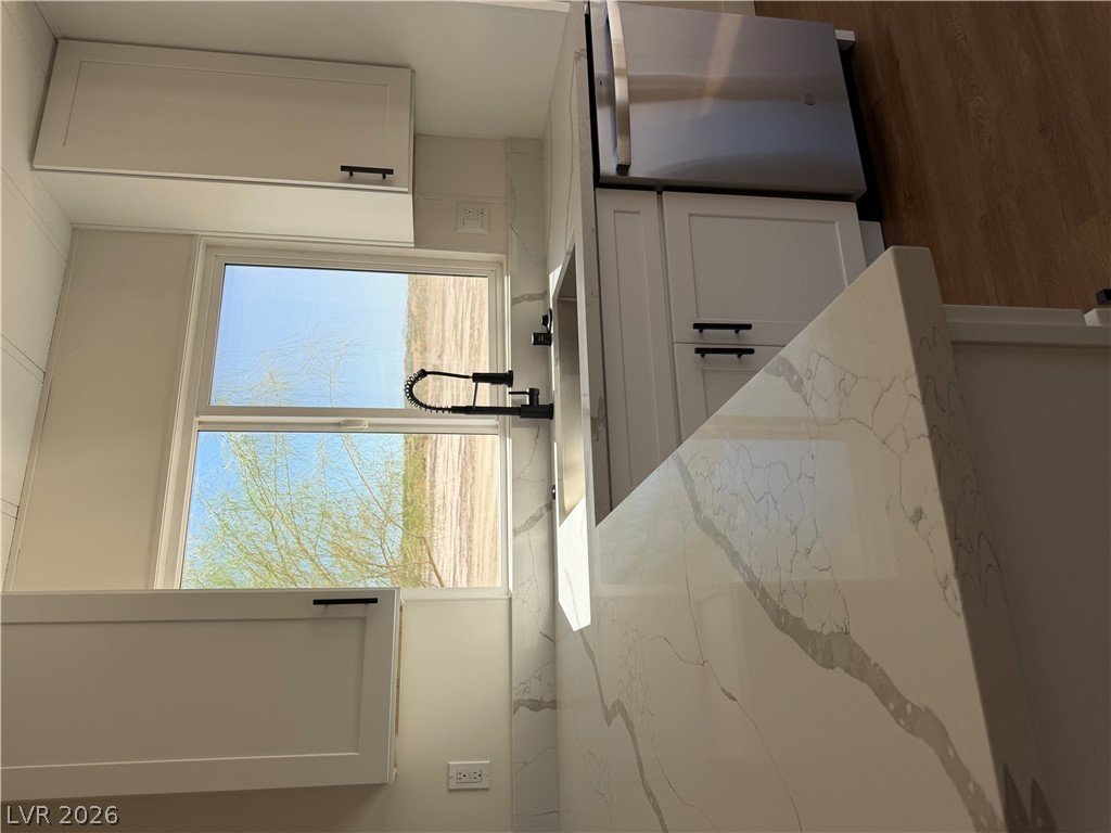 6401 Hafen Ranch Road Pahrump, NV 89061 - Photo 11 of 22 Gleaming stone countertops and shaker cabinetry frame a window over the kitchen sink.