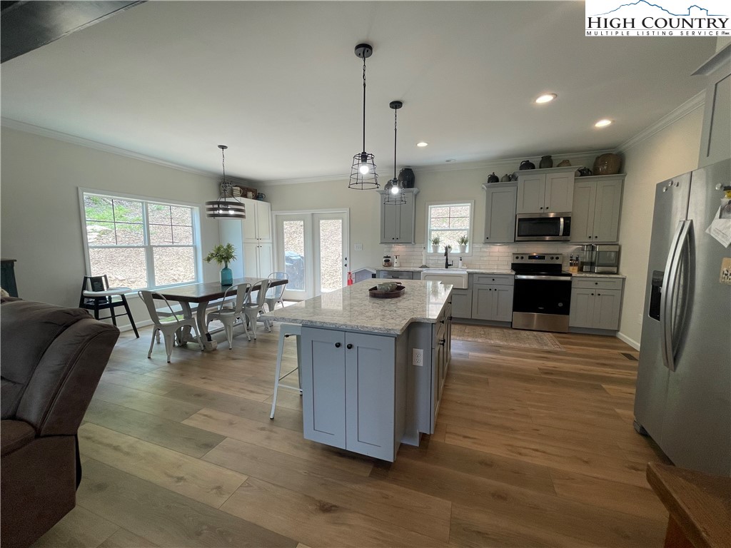 878 Ballou Farm Road Crumpler, NC 28617 - Photo 19 of 45 a kitchen with stainless steel appliances granite countertop a refrigerator a stove a sink dishwasher a dining table and chairs with wooden floor
