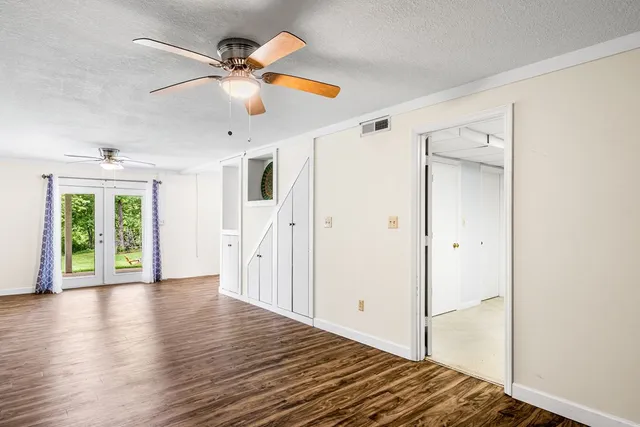 a view of an empty room with window and wooden floor