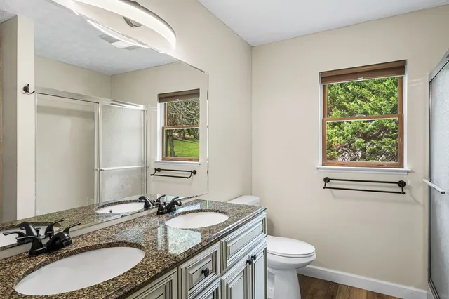 a bathroom with a granite countertop sink toilet and a mirror
