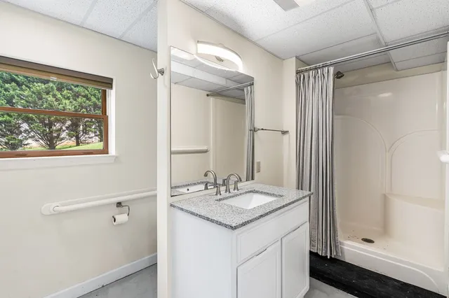 a bathroom with a granite countertop sink a mirror and a shower