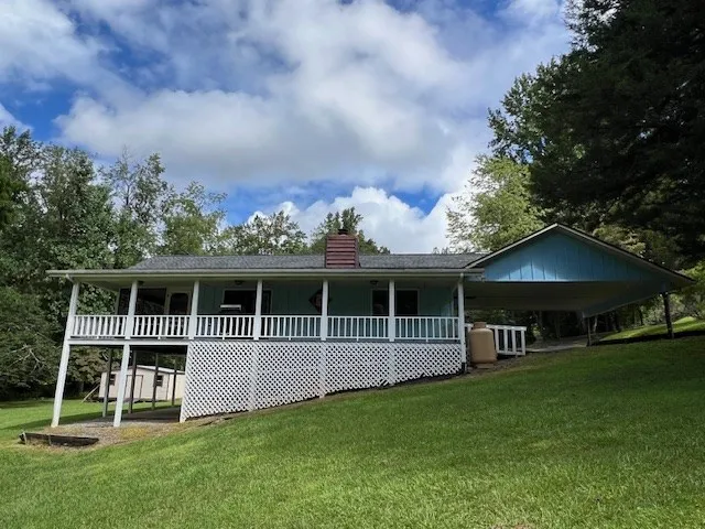 a view of a house with a wooden deck and a big yard