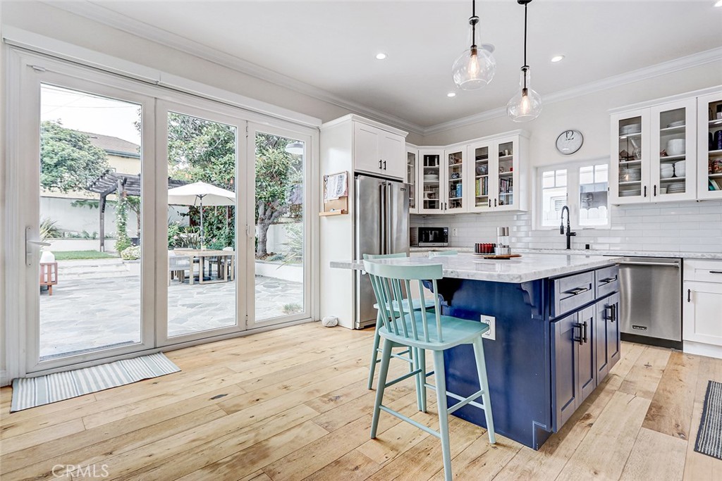 825 Center Street El Segundo, CA 90245 - Photo 13 of 52 a kitchen with stainless steel appliances granite countertop a stove a refrigerator a sink dishwasher a dining table and chairs with wooden floor