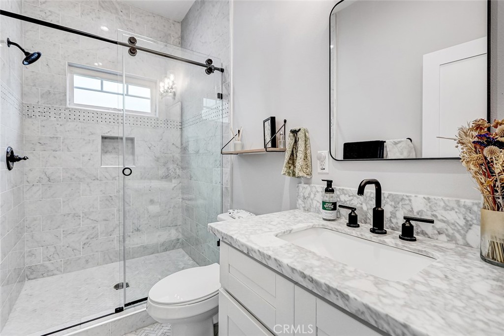 825 Center Street El Segundo, CA 90245 - Photo 29 of 52 a bathroom with a granite countertop sink a toilet a mirror and shower