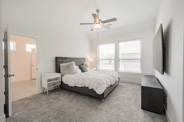 a spacious bedroom with a bed and a flat tv screen on dresser